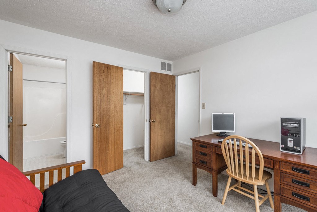 a bedroom with a desk and a chair and a closet