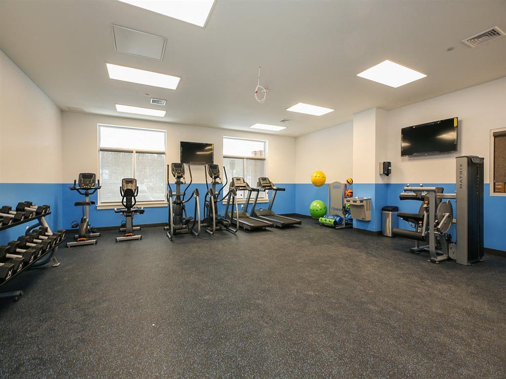 a gym with cardio equipment and weights on the floor