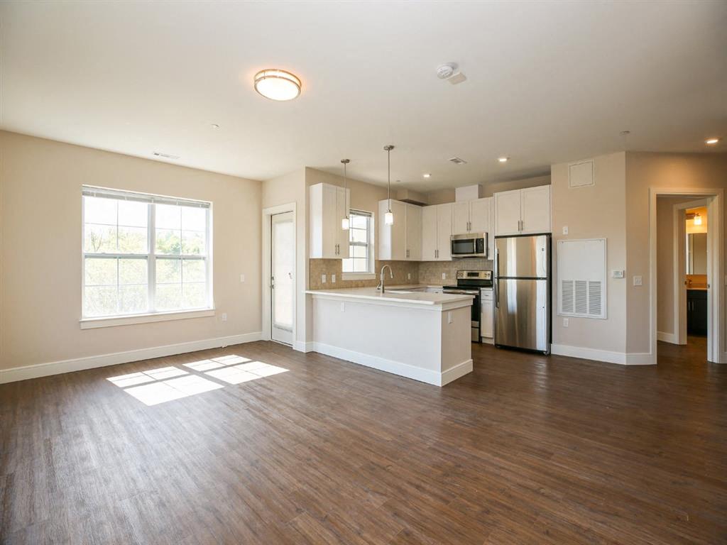 an empty living room and kitchen with a refrigerator and a sink