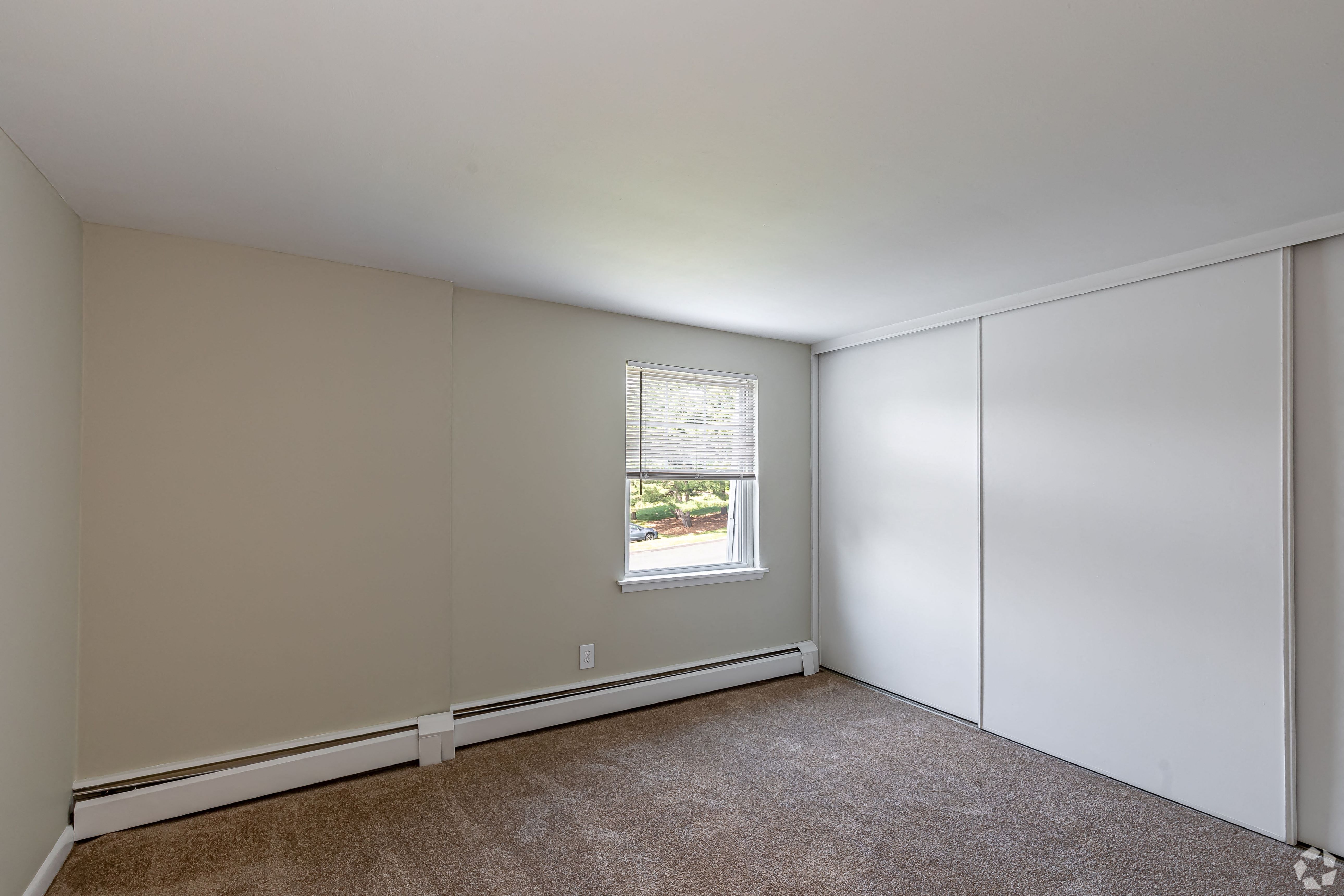 an empty bedroom with white walls and a window
