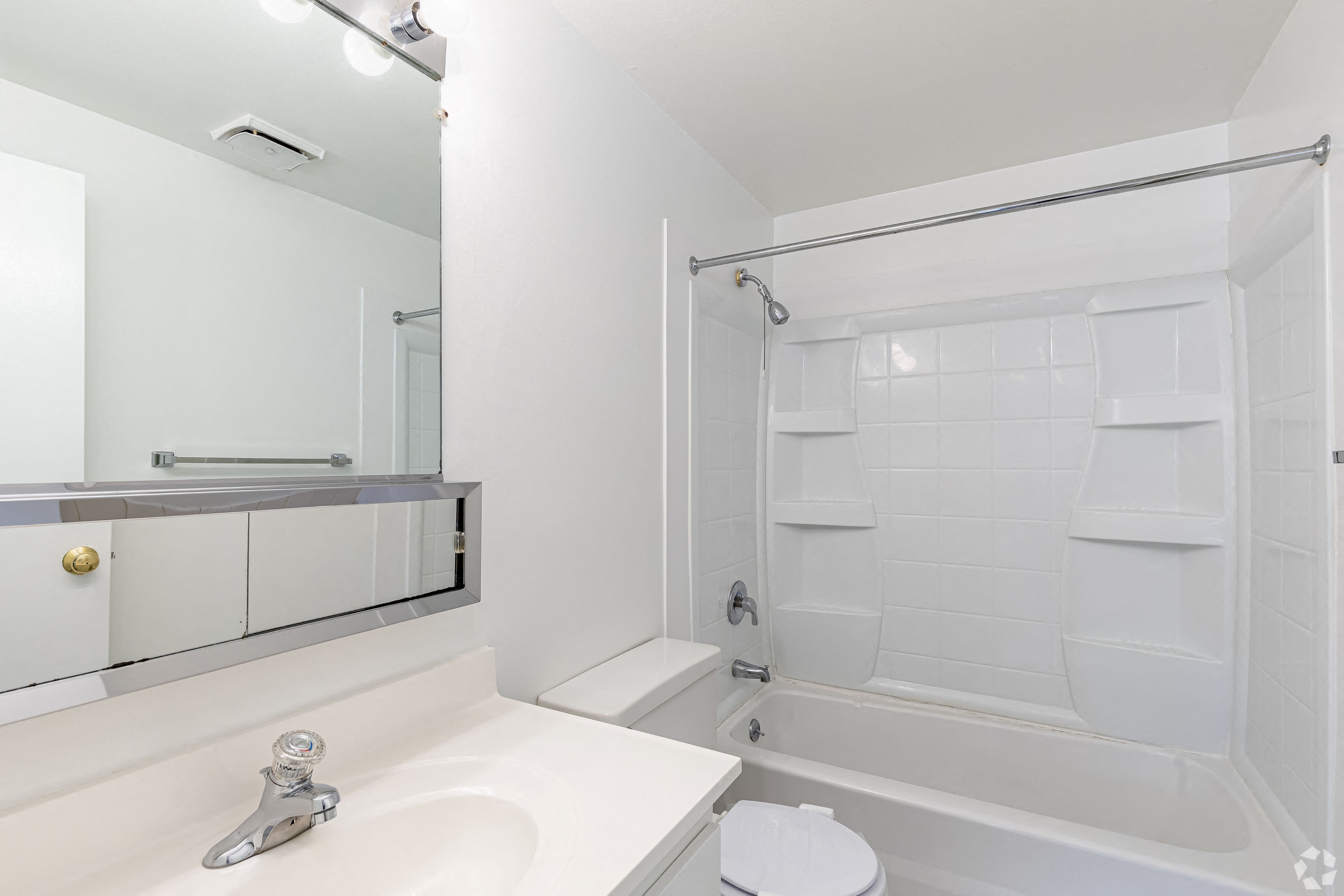 a white bathroom with a tub and a sink and a mirror