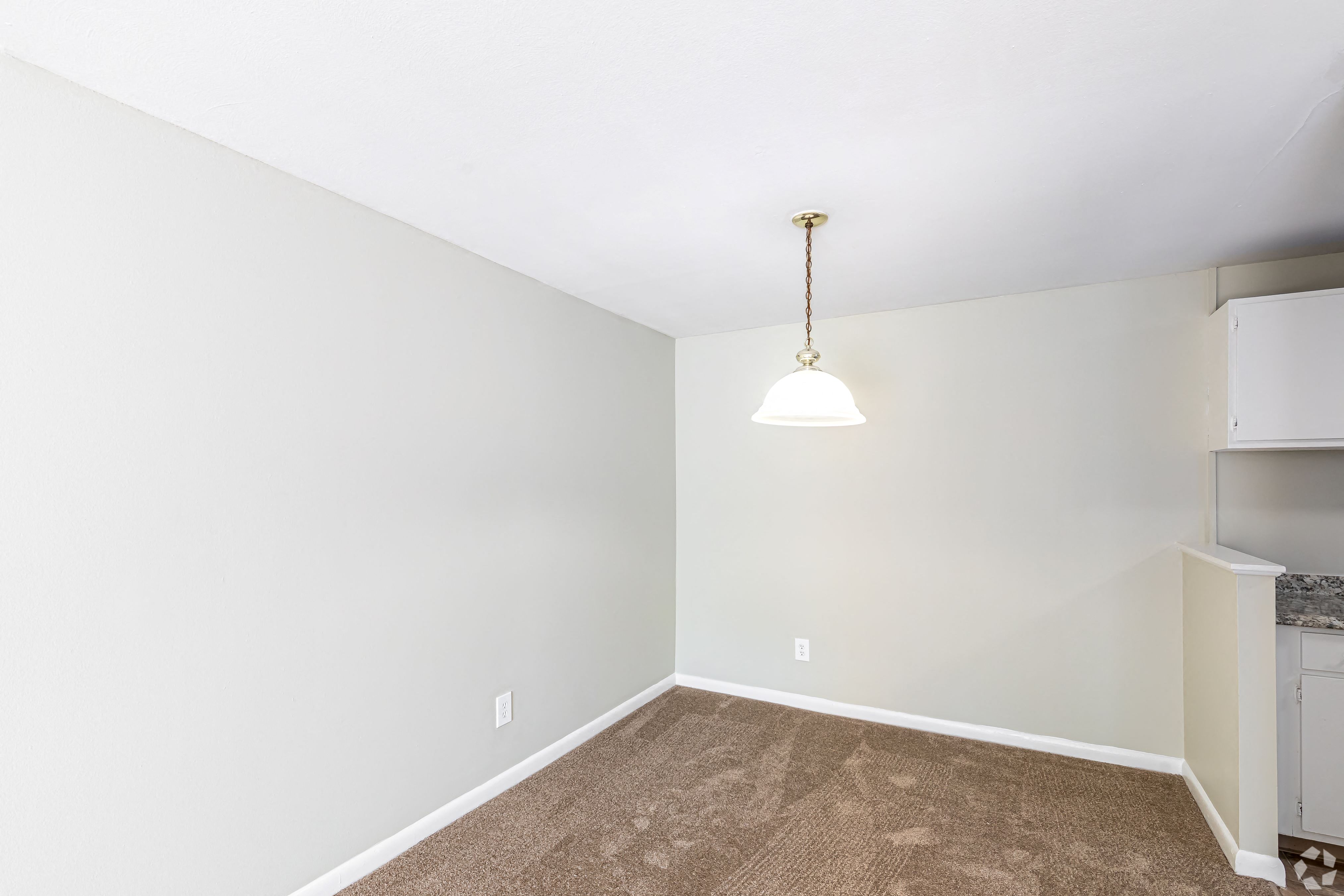 an empty room with a white wall and a ceiling lamp