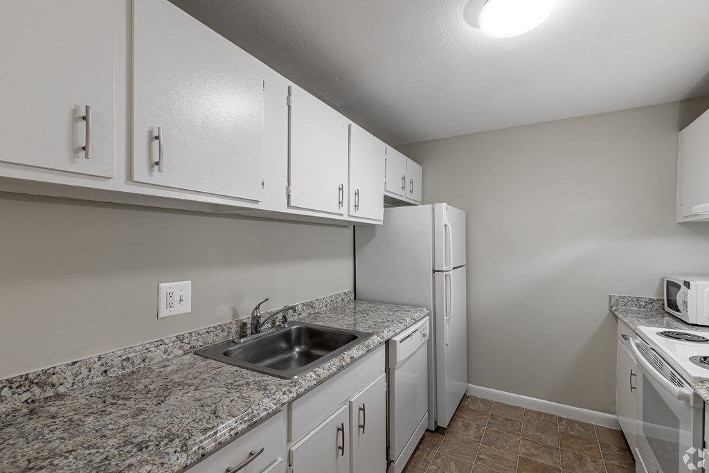 a kitchen with white appliances and granite counter tops and a sink