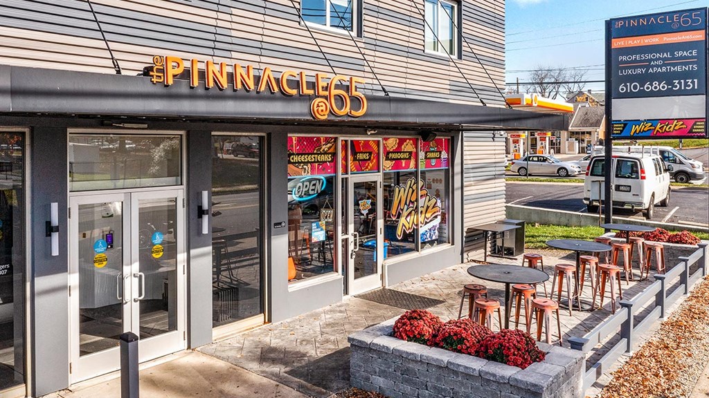 the front of a store with tables and chairs outside of it