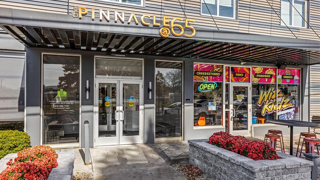 the front of a store with glass doors and a sign