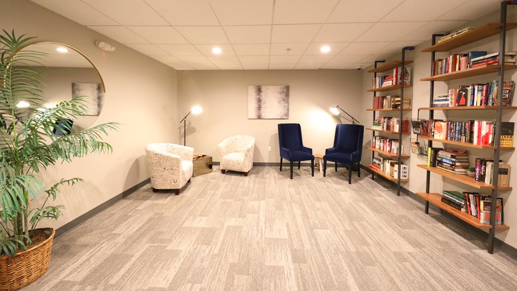 a room with a library with chairs and bookshelves