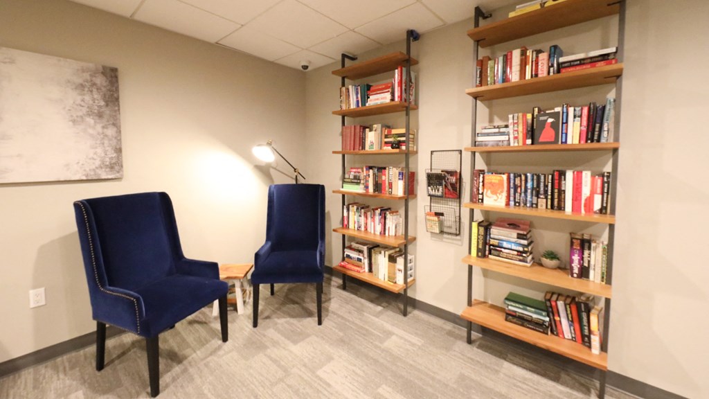 a room with two blue chairs and a bookshelf filled with books
