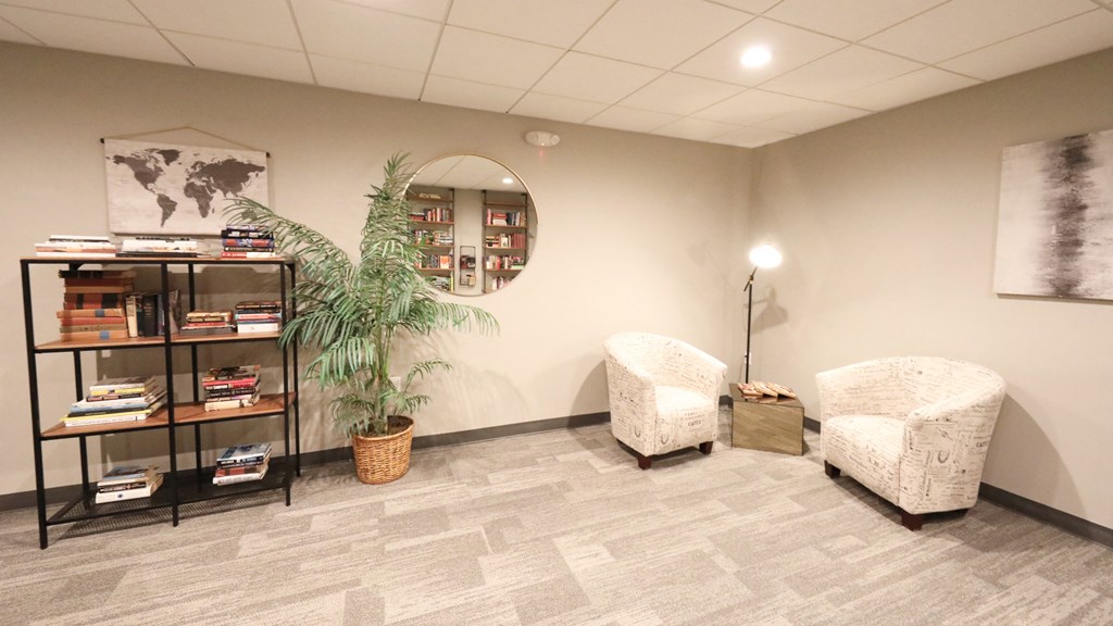 a living room with two chairs and a bookshelf and a mirror