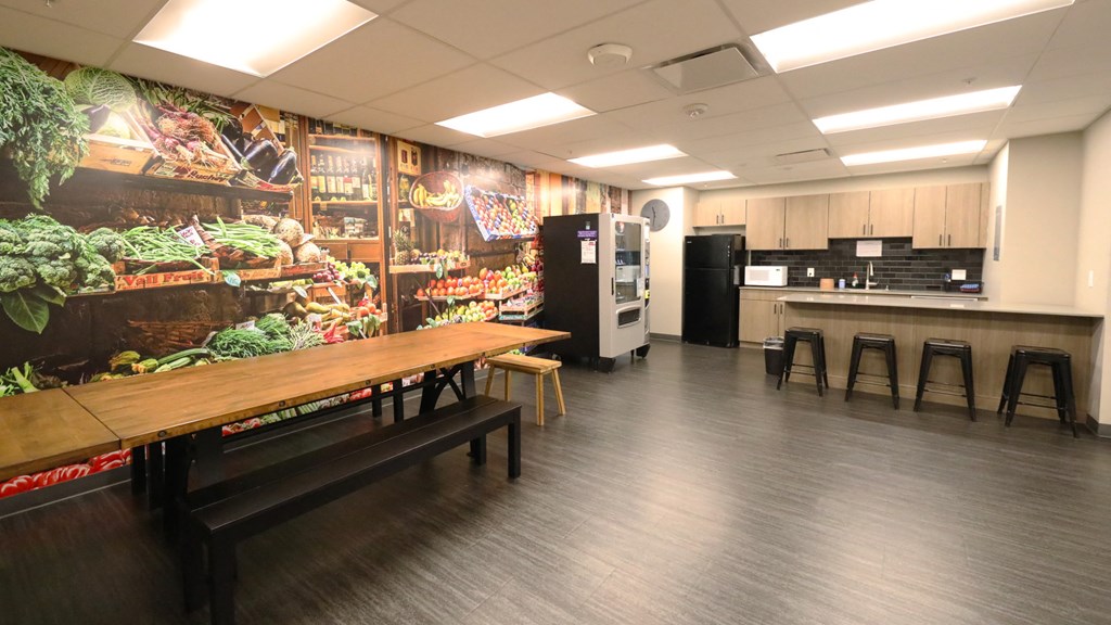a dining room with a table and stools in front of a mural of food