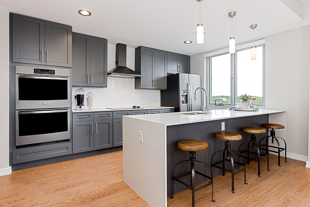 a kitchen with gray cabinets and a large island with stools