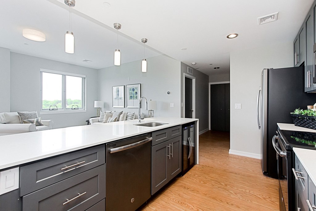 an open kitchen and living room with a refrigerator and a sink