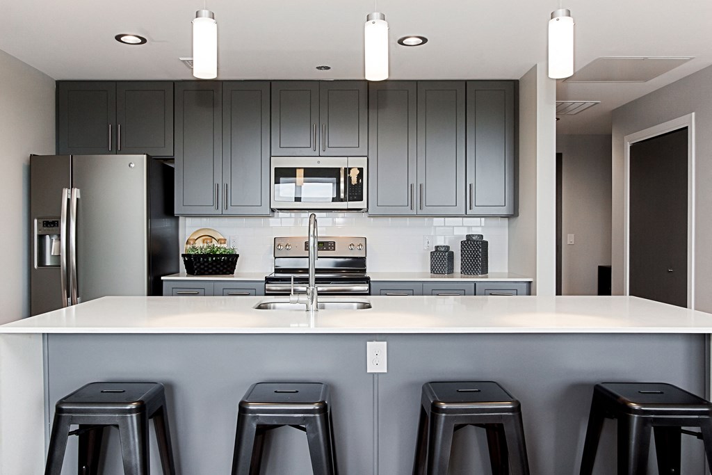 a kitchen with bar stools and gray cabinets