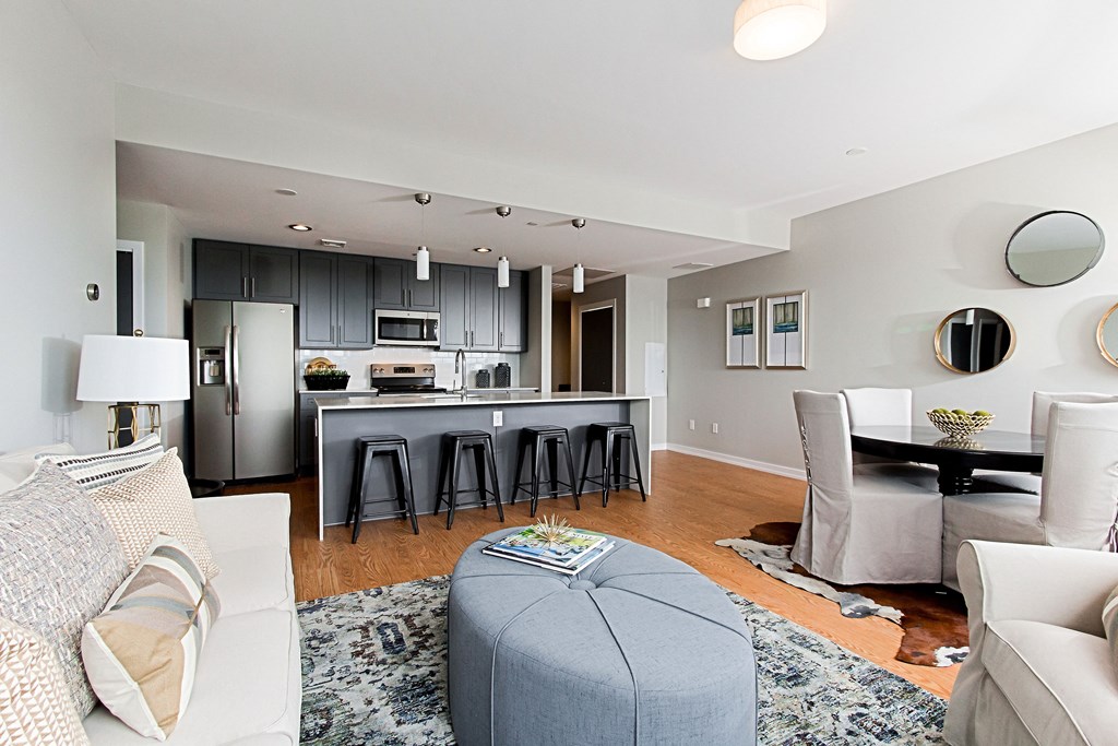 a living room with a kitchen and a couch and chairs