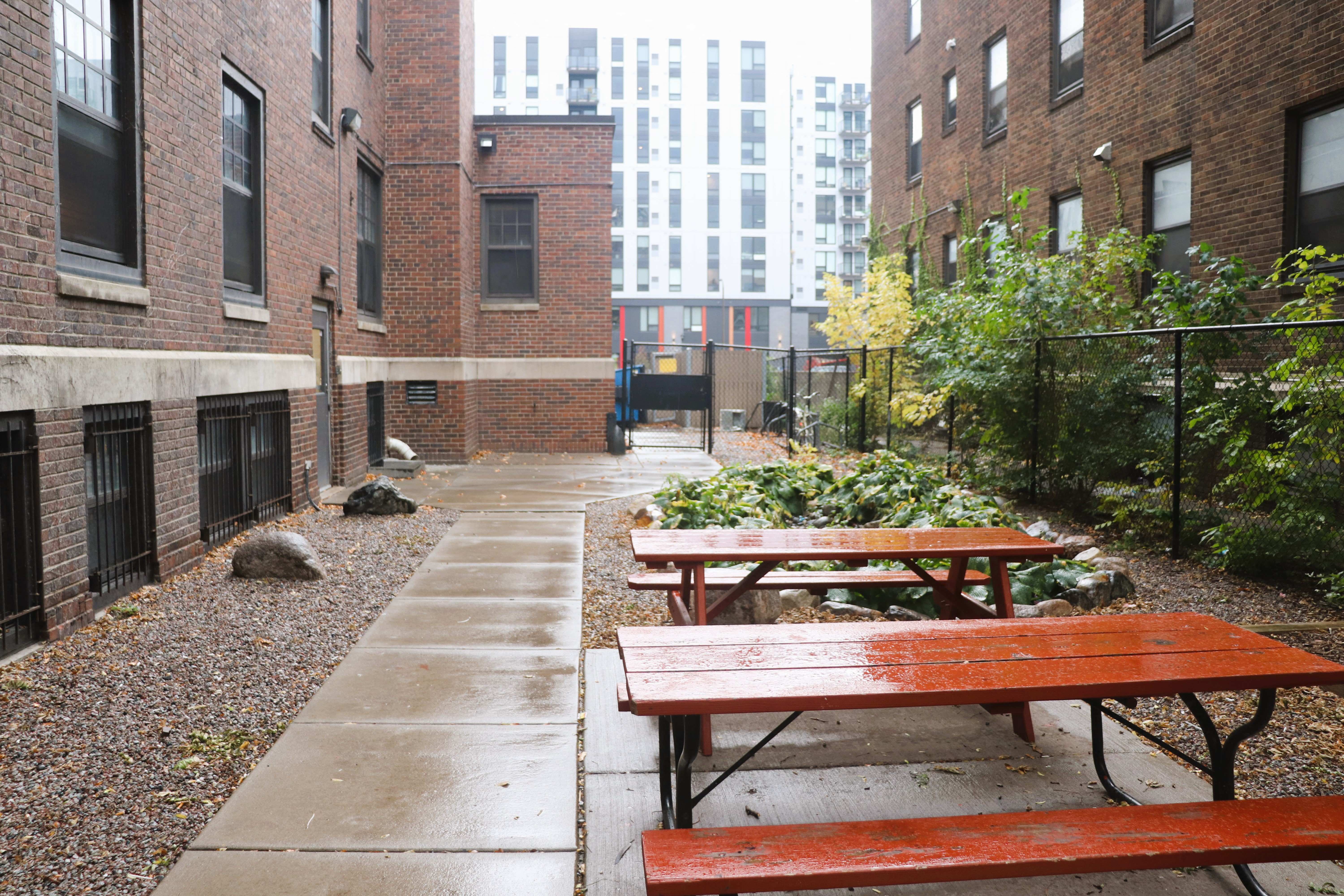 two benches and a picnic table in a courtyard with buildings