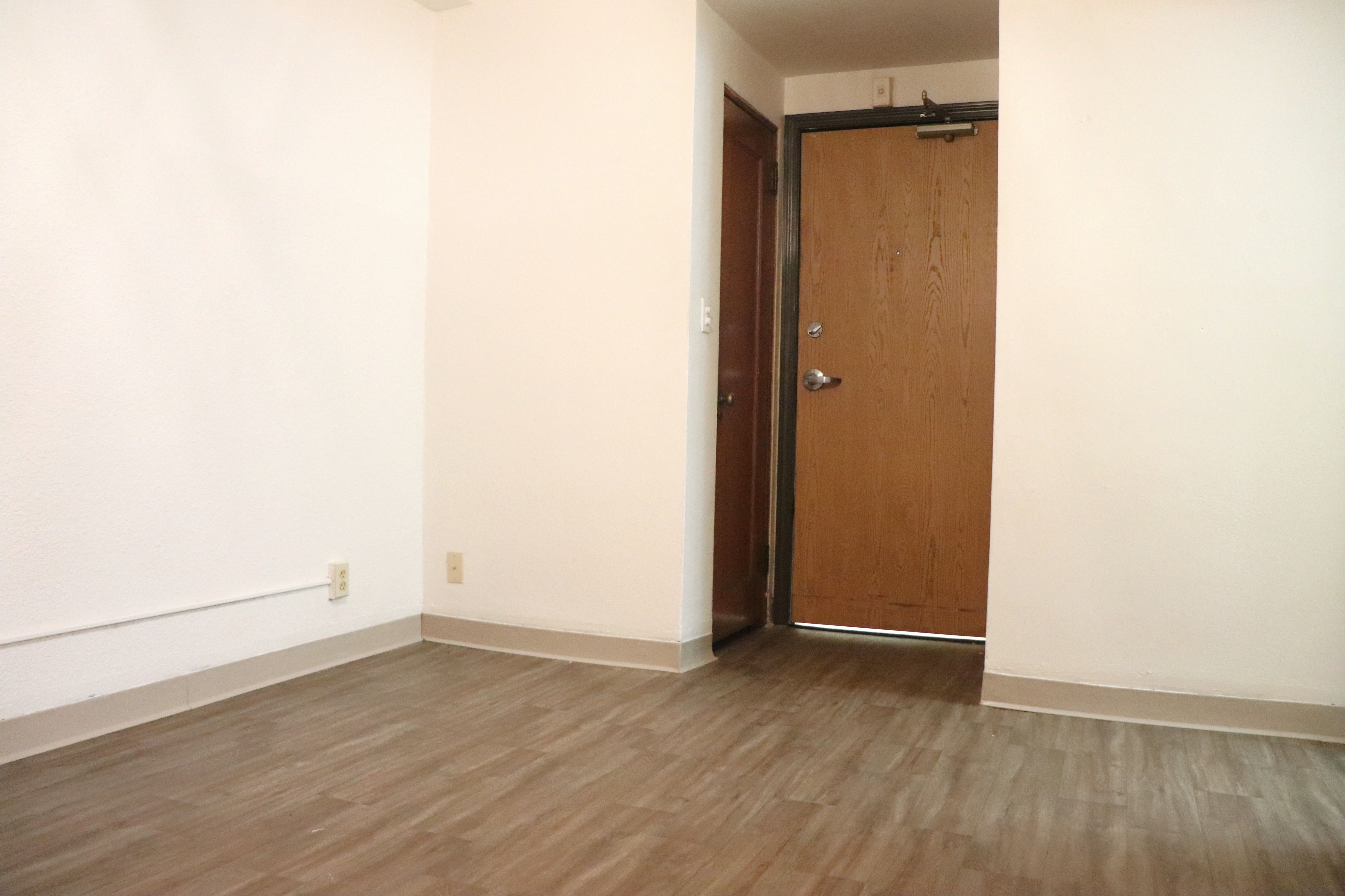 an empty room with a wooden floor and a wooden door