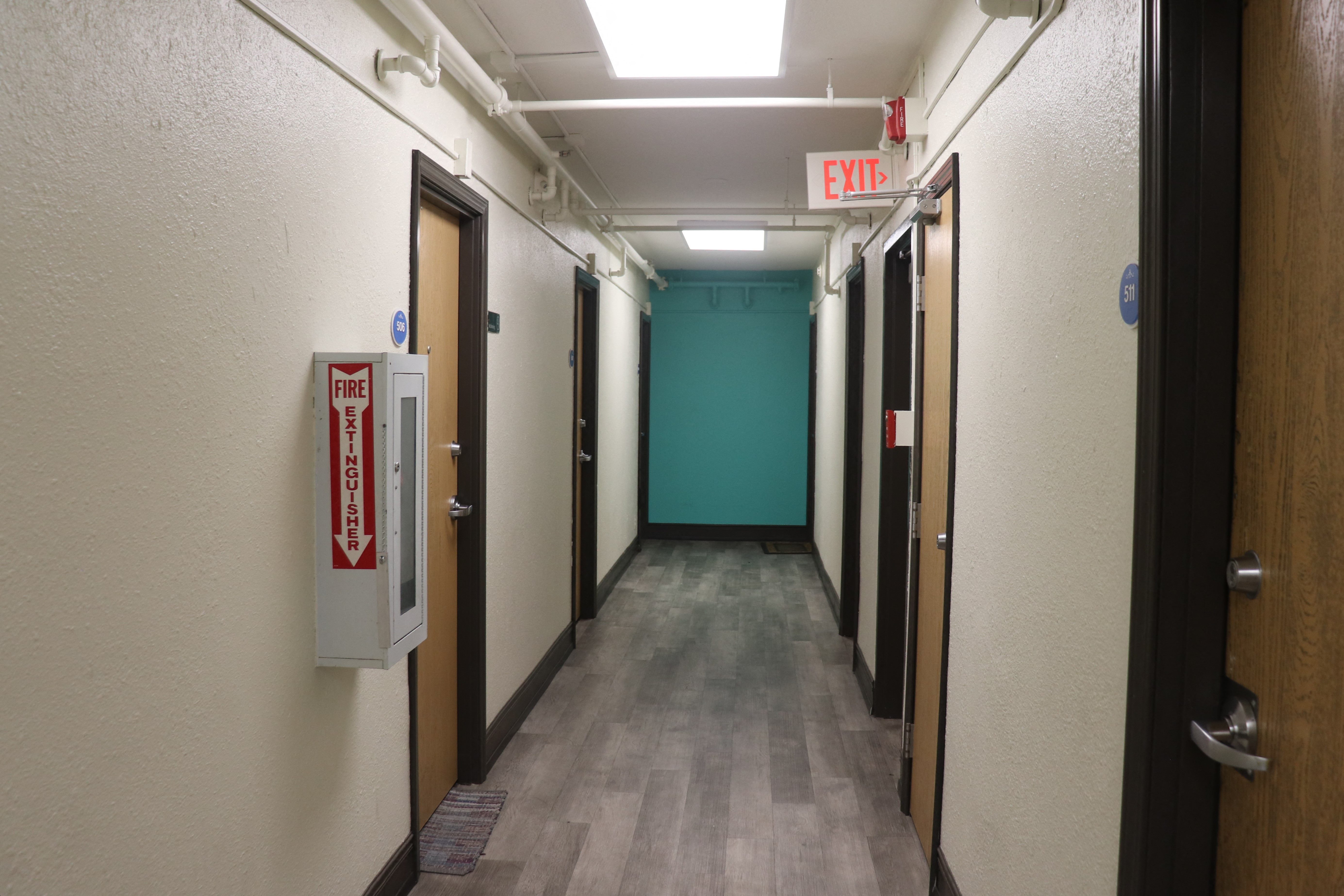 a hallway with doors and a exit sign in a building