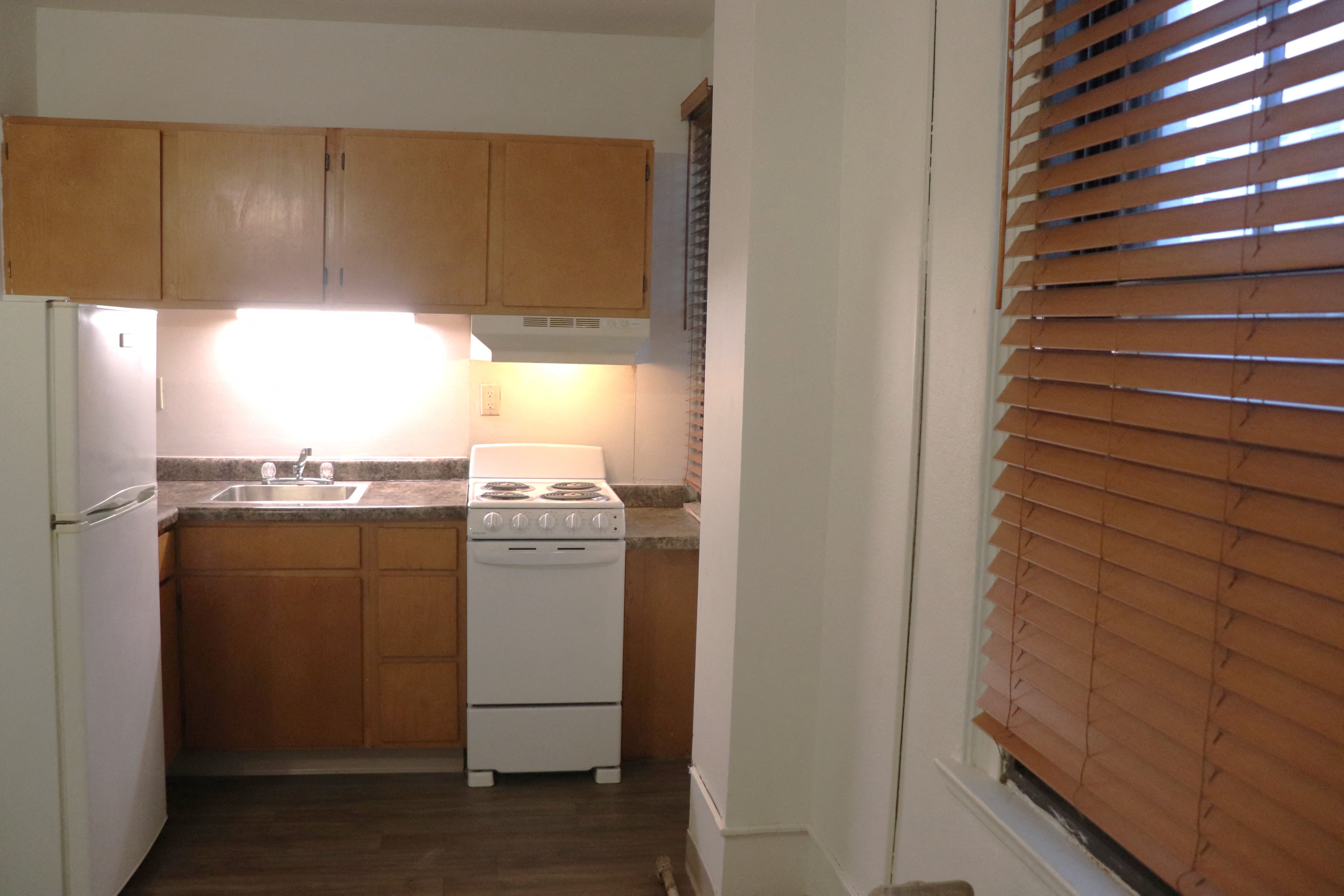a kitchen with wooden cabinets and a white stove and refrigerator