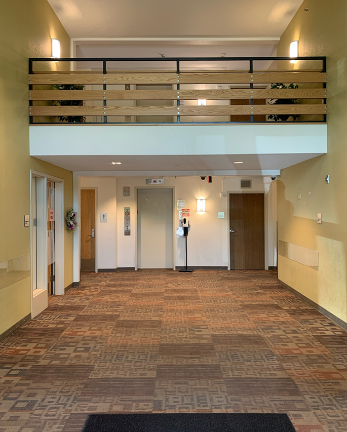 Entrance lobby area with a large open space and lofted area to second floor. Elevator can be seen in the background