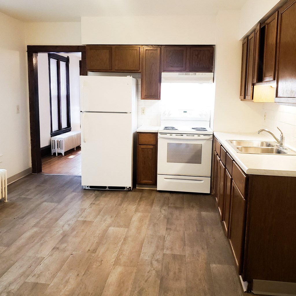an empty kitchen with wooden cabinets and a white refrigerator