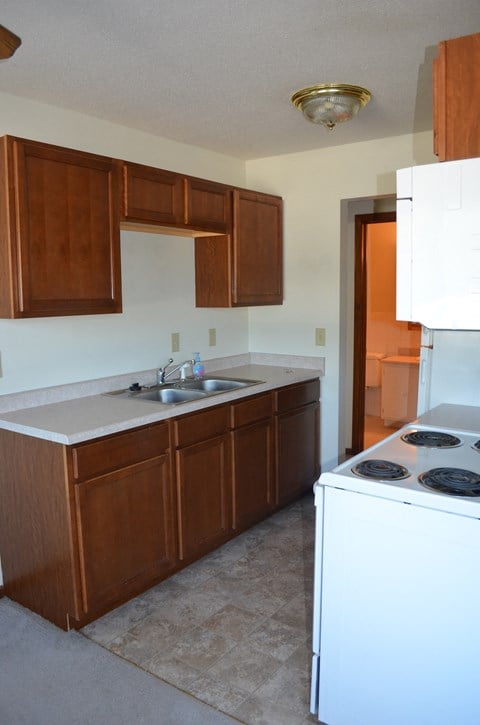 a kitchen with wooden cabinets and a white stove and sink