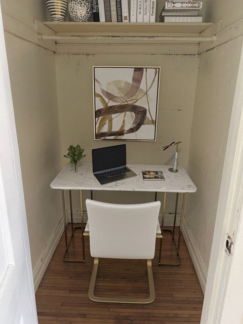 a small desk with a laptop and a chair in a small room