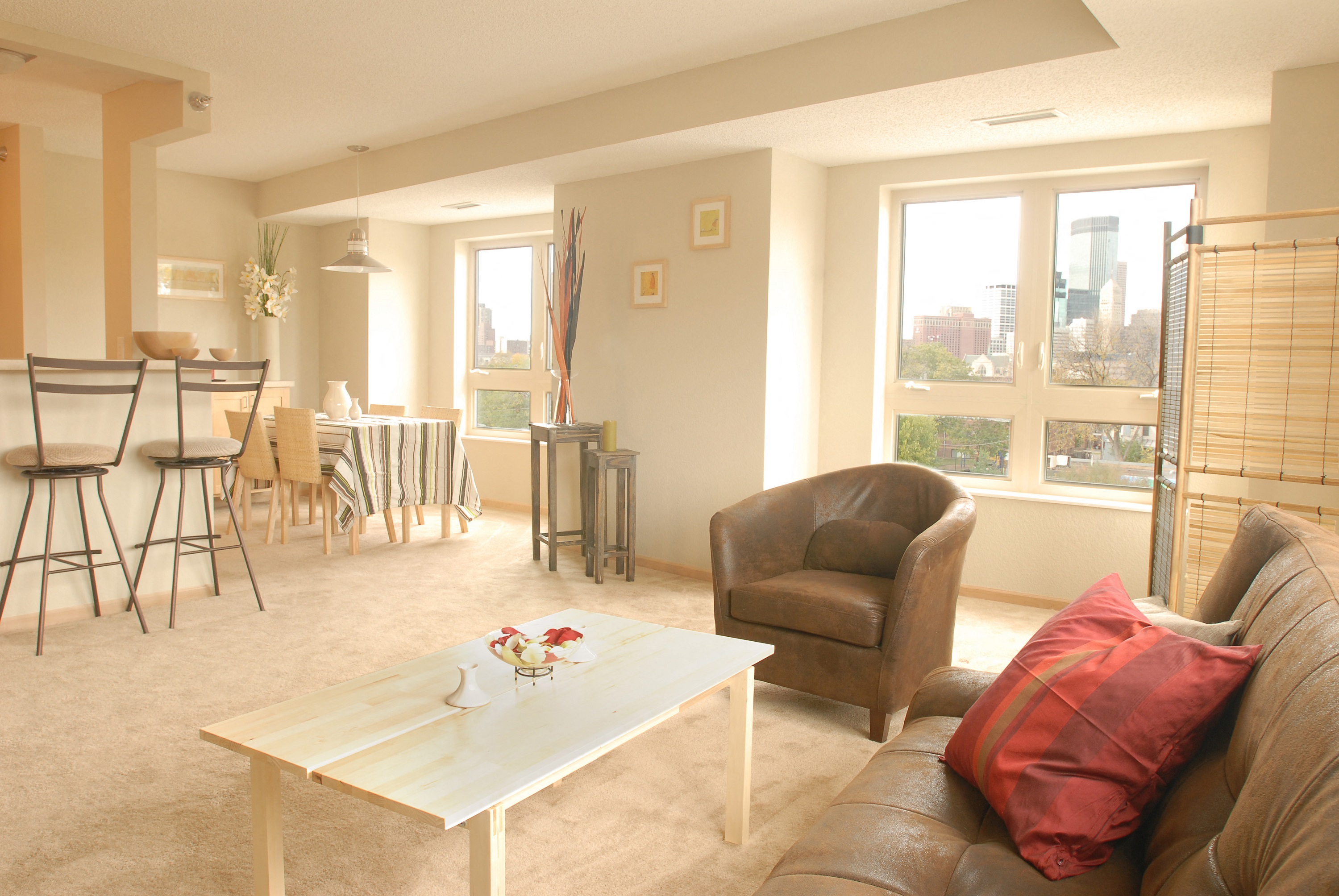 a living room with a couch and a chair in front of a dining room table