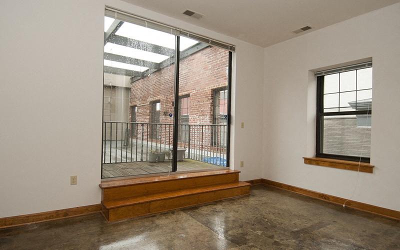 an empty living room with a large window and a balcony