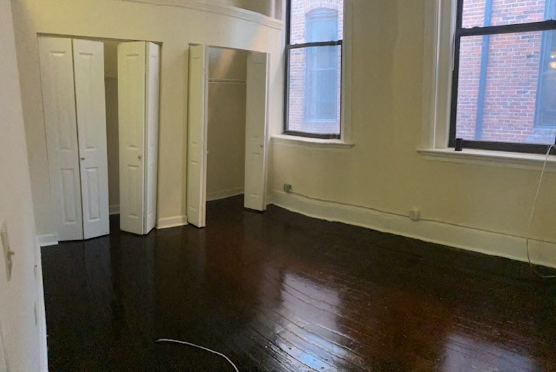 an empty room with wooden floors and three doors