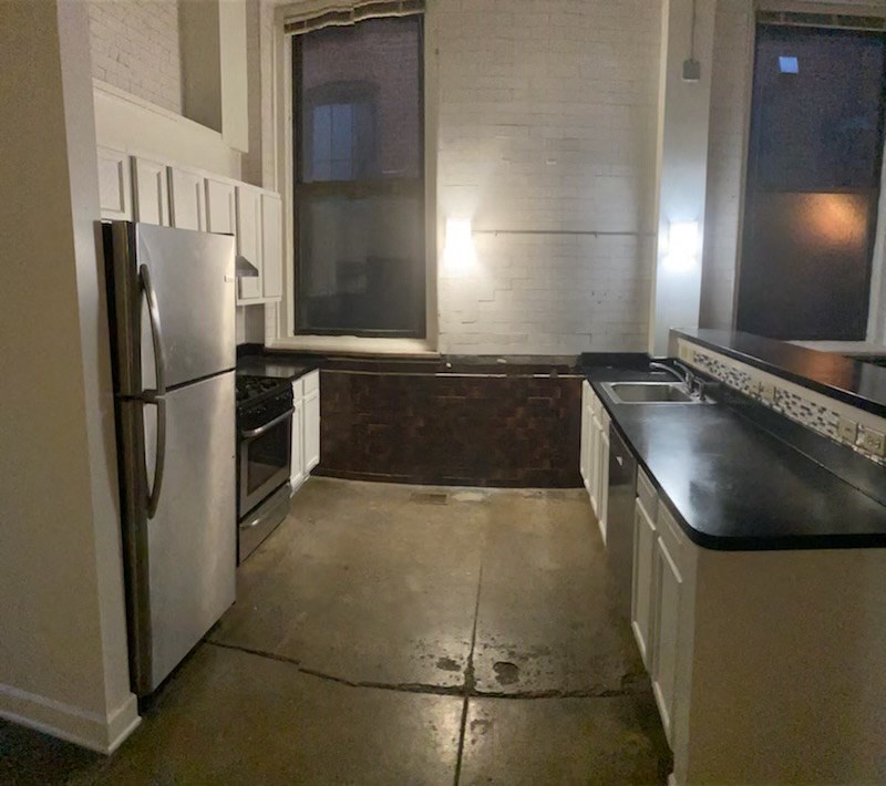 an empty kitchen with a refrigerator and a window