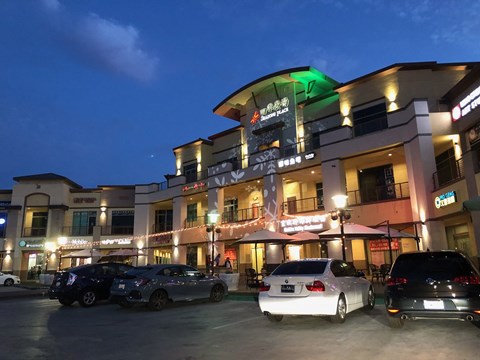 A white car is parked in front of a building with a green light on.