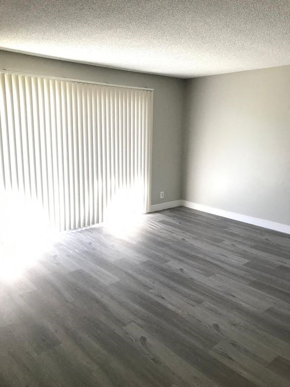 an empty living room with wood floors and a window