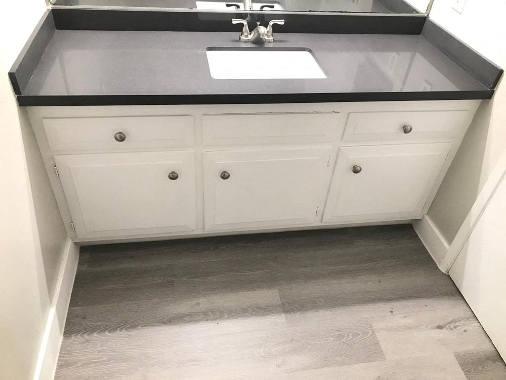 a white bathroom with a sink and a black counter top