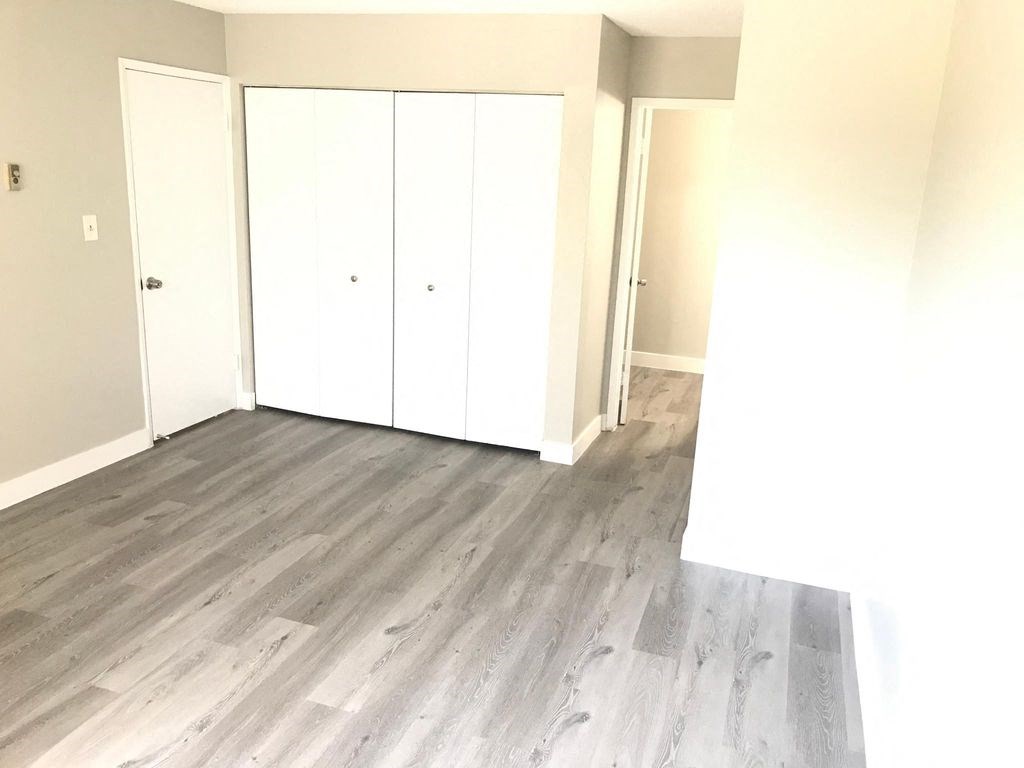 an empty room with wood floors and white closets