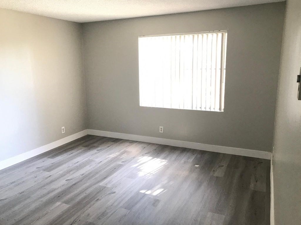 an empty room with wooden floors and a window