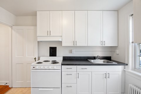 a kitchen with white cabinets and a white stove and sink