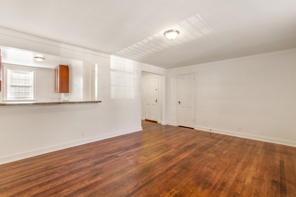 an empty living room with wood floors and white walls