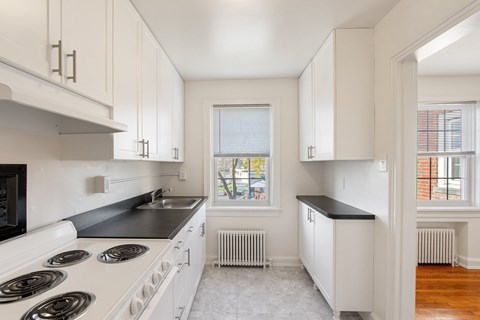 a kitchen with white cabinets and a stove and a window