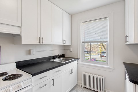 a kitchen with white cabinets and a sink and a window