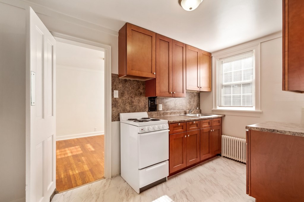 a kitchen with brown cabinets and white appliances and a window
