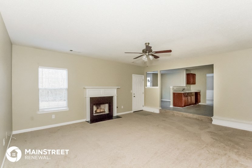 an empty living room with a fireplace and a ceiling fan