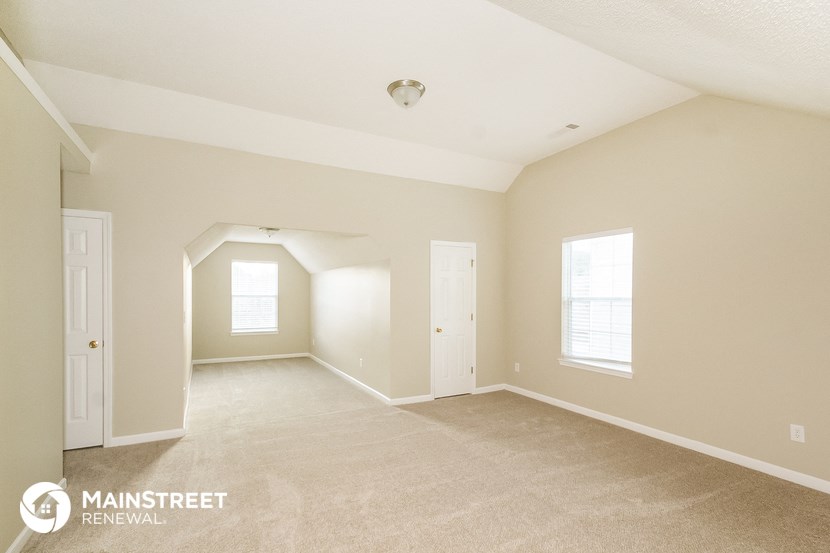 the spacious living room with carpeted flooring and white walls