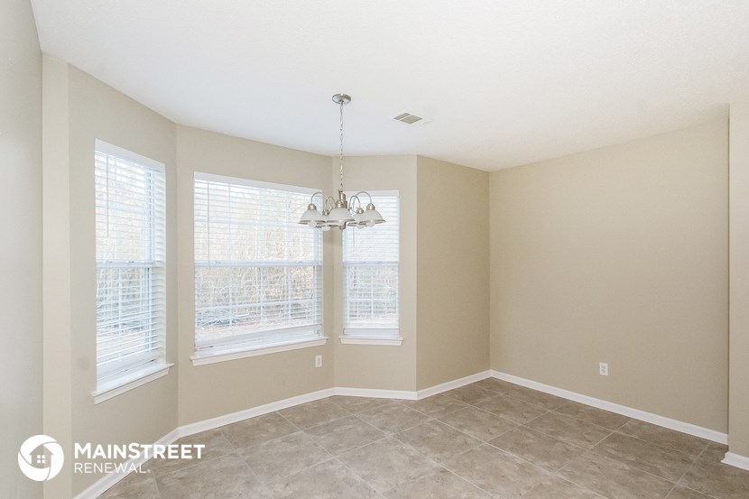 a living room with three windows and a chandelier