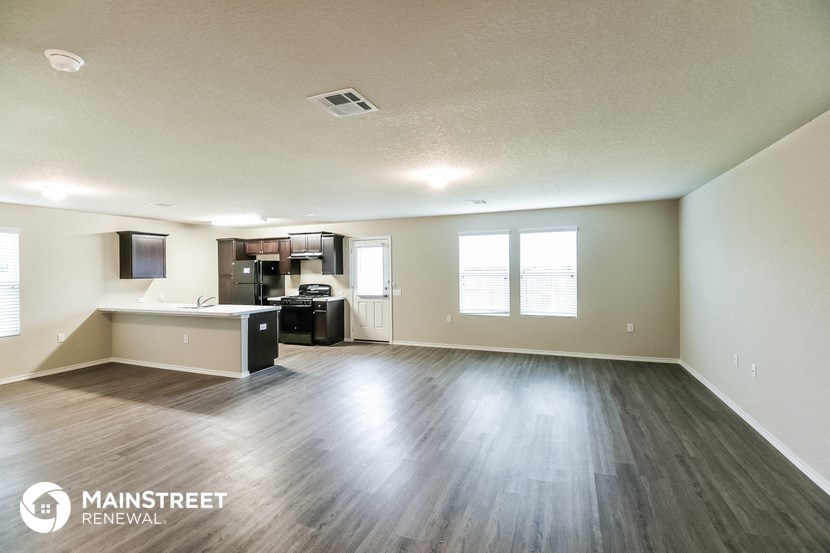 the spacious living room and kitchen of an apartment