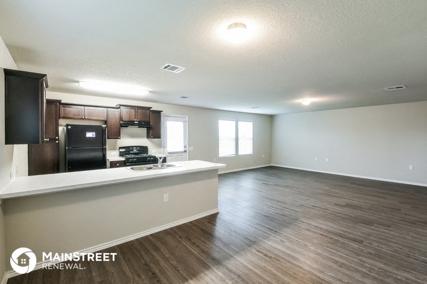 the living room and kitchen of an apartment with wood flooring