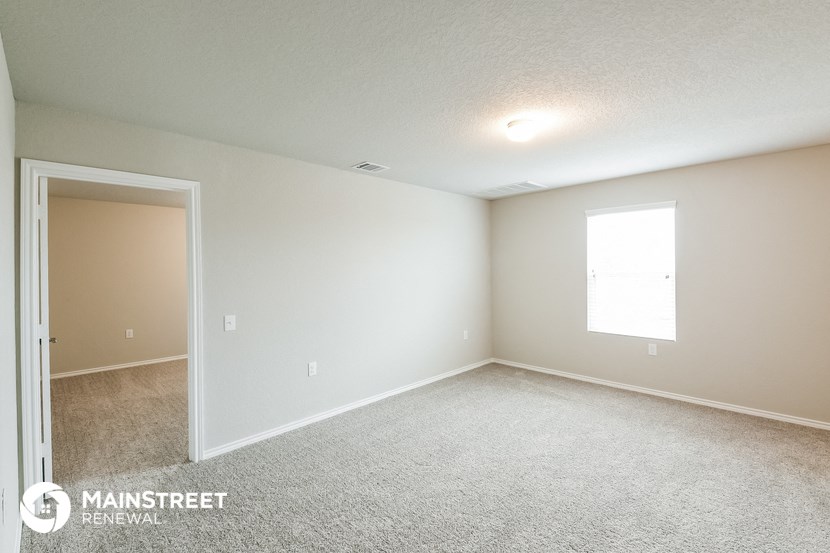 the spacious living room with carpeted flooring and white walls