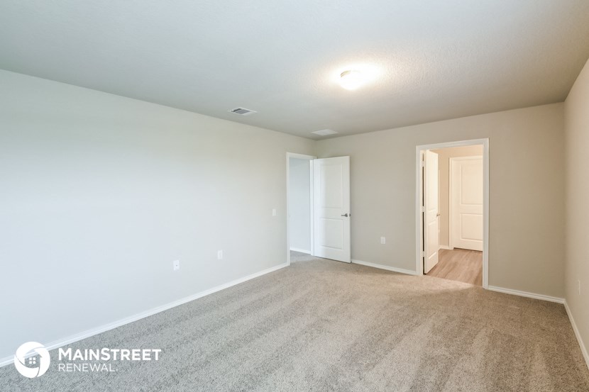 the spacious living room with carpeting and a door to the hallway