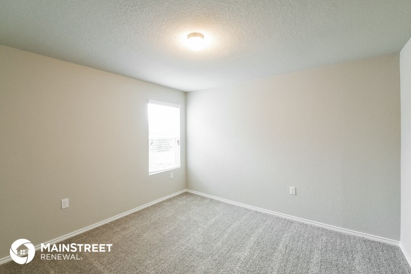 the spacious living room with carpeting and a window
