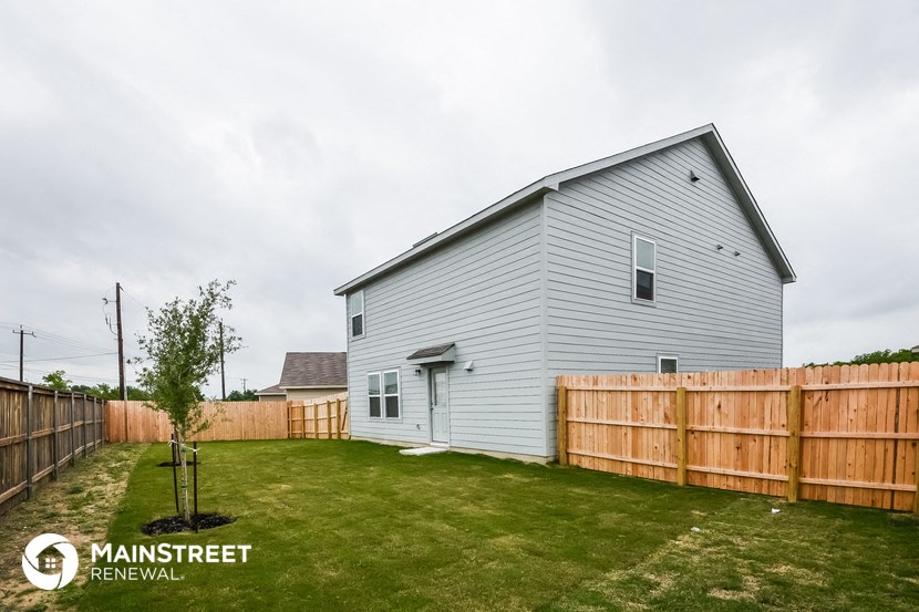 a backyard with a white house and a wooden fence