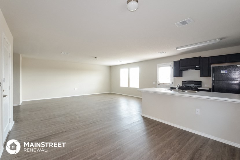 an empty living room and kitchen with wood flooring