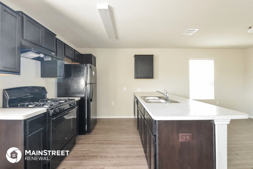 an updated kitchen with black appliances and white countertops in a new home
